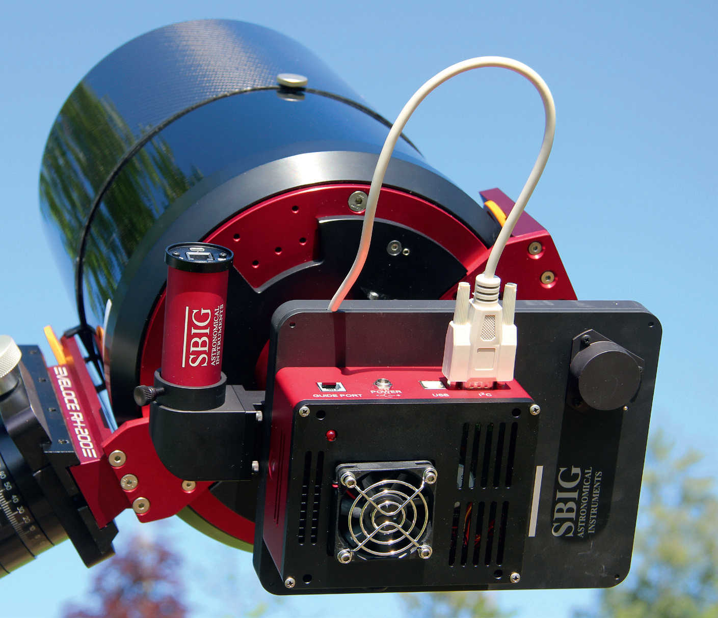 Chłodzona kamera CCD na astrografie: pomiędzy teleskopem a kamerą (czerwono-czarna obudowa) widać (również czarne) koło filtrowe, a obok okrągłą kamerę prowadzącą (czerwoną), która jest umieszczona w torze wiązki optycznej poprzez guider off-axis. U. Dittler