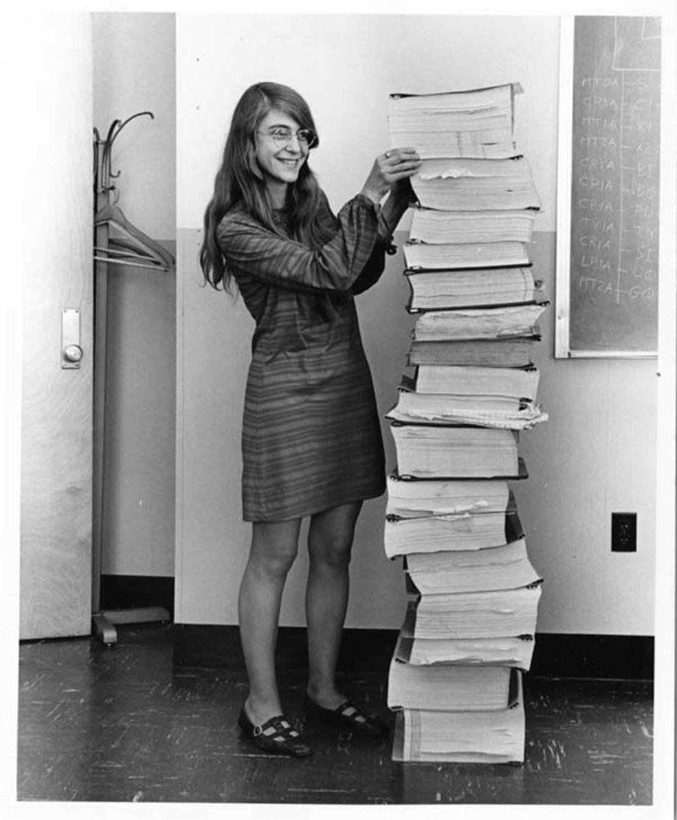 Margaret Hamilton posant à côté d’une pile des manuels contenant le code du logiciel de navigation d’Apollo. © Avec l’aimable autorisation du Musée du Massachusetts Institute of Technology